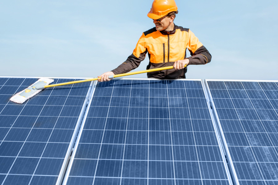 man wiping solar panel with a mop